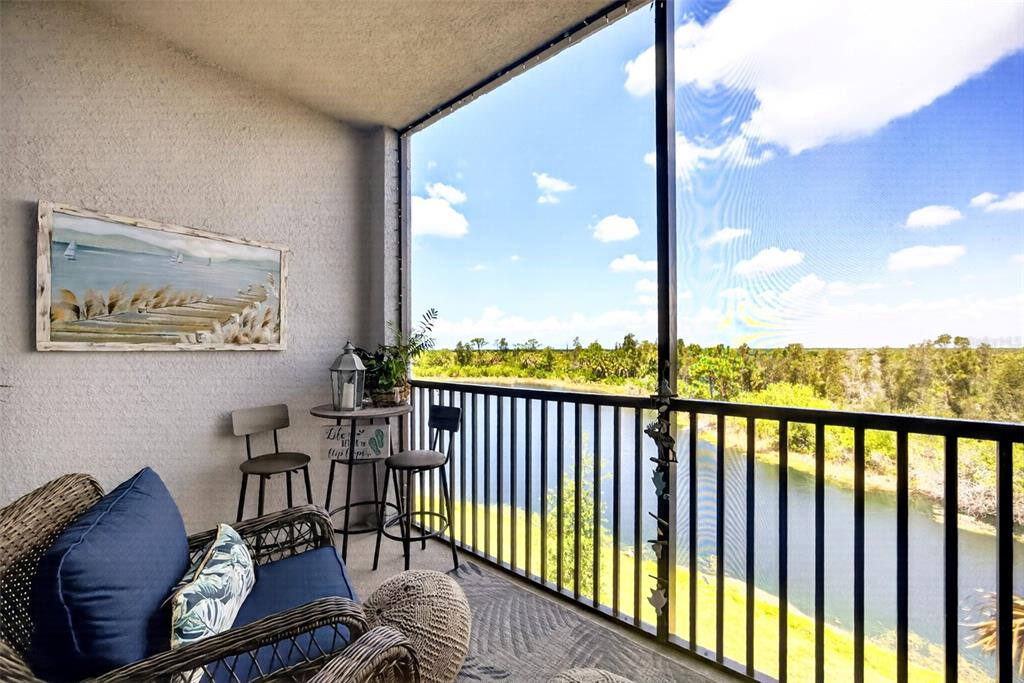 A screened-in balcony features a wicker chair, a small bistro set, and a water view — 14141 HERITAGE LANDING BOULEVARD UNIT 934, PUNTA GORDA, FL