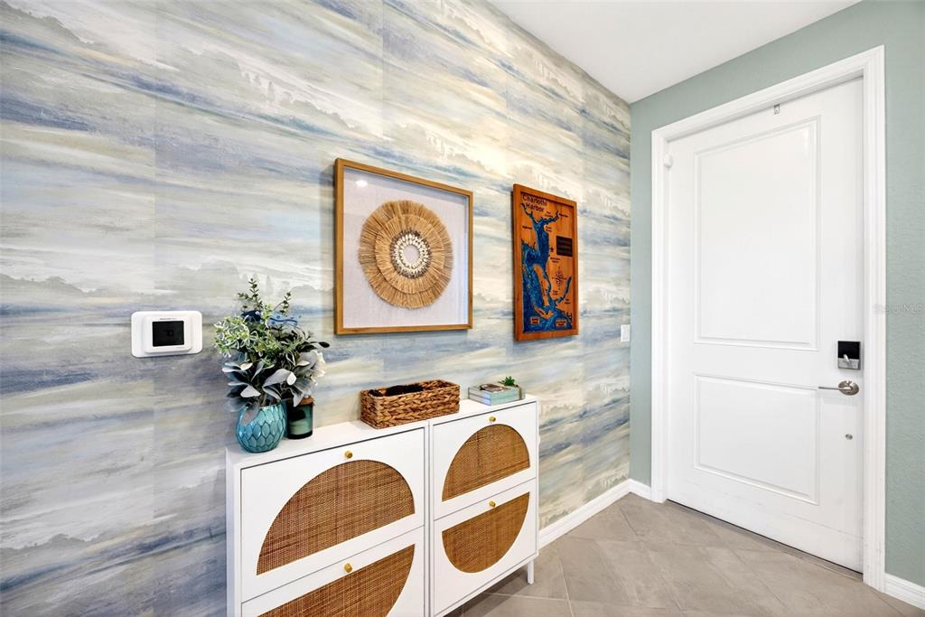 An entryway features patterned wallpaper, a white cabinet with rattan accents, and a white door — 14141 HERITAGE LANDING BOULEVARD UNIT 934, PUNTA GORDA, FL