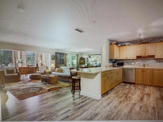 An open-concept living room and kitchen feature light wood cabinets and wood-look flooring — 300 N Highway A1a # 204a, Jupiter FL 33477, JUPITER, FL
