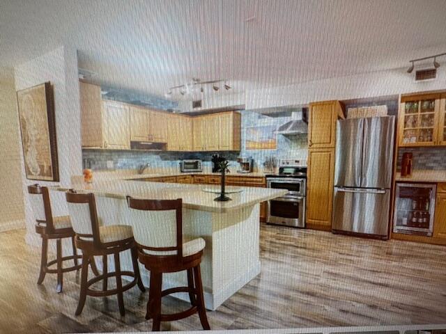 A kitchen features light wood cabinets, a central island with bar stools, and stainless appliances — 300 N Highway A1a # 204a, Jupiter FL 33477, JUPITER, FL
