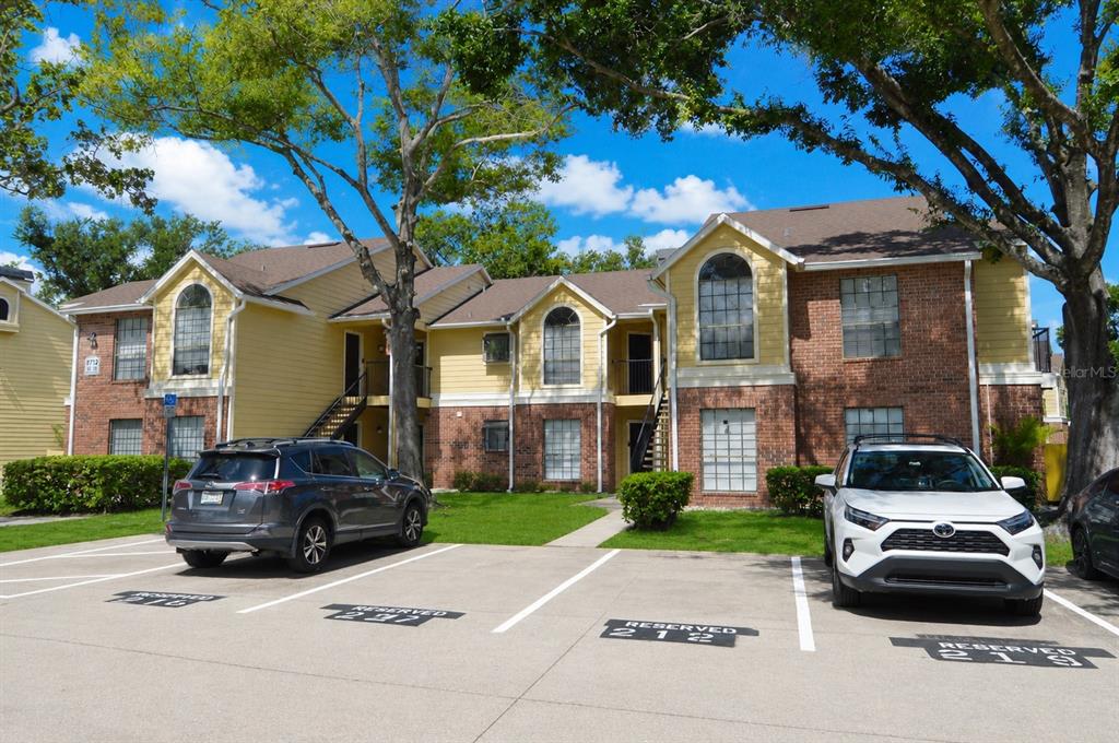 A two-story apartment building with brick and yellow siding features reserved parking spaces out front — 8714 MALLARD RESERVE DRIVE UNIT 201, TAMPA, FL