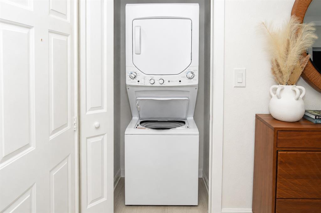 A white stacked washer and dryer unit sits inside a small closet — 8714 MALLARD RESERVE DRIVE UNIT 201, TAMPA, FL