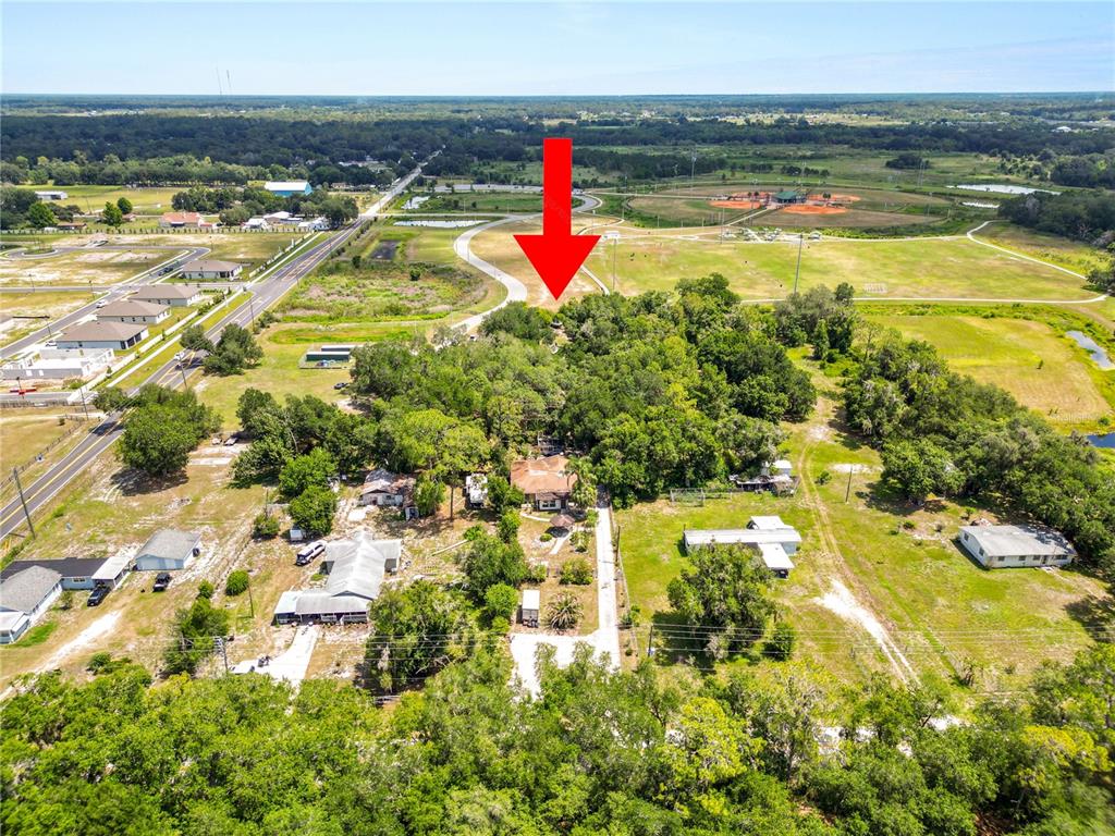 An aerial view shows a residential property surrounded by trees, fields, and a nearby road — 4125 SWINDELL ROAD, LAKELAND, FL