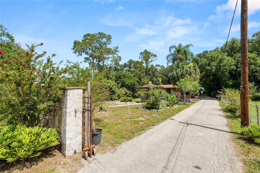 A gravel driveway leads toward a house surrounded by trees and a gated entrance — 4125 SWINDELL ROAD, LAKELAND, FL