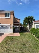 A two-story tan stucco house with a white garage door and a palm tree — 16870 SW 142nd Pl # 1, Miami FL 33177, MIAMI, FL