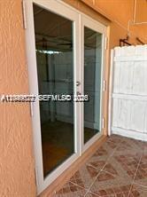 A white-framed glass double door opens onto a tiled patio next to a privacy fence — 16870 SW 142nd Pl # 1, Miami FL 33177, MIAMI, FL