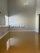 An empty room with high ceilings, light gray walls, and glossy tan tile flooring — 16870 SW 142nd Pl # 1, Miami FL 33177, MIAMI, FL