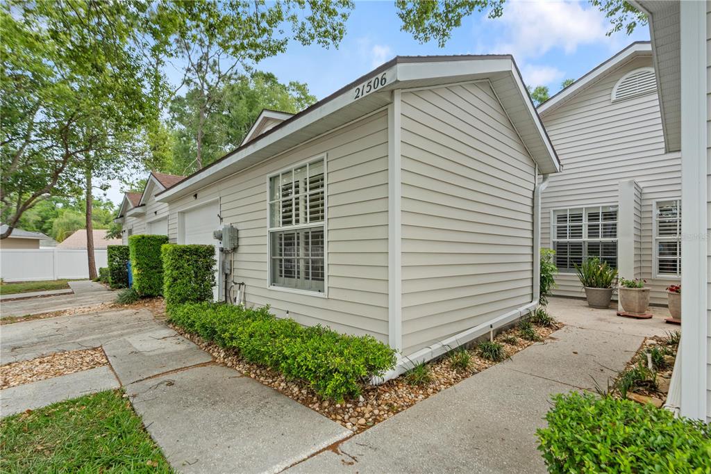A light-colored vinyl-sided house exterior features a garage, a window, and a concrete walkway — 21506 GRAY TERN COURT, LUTZ, FL