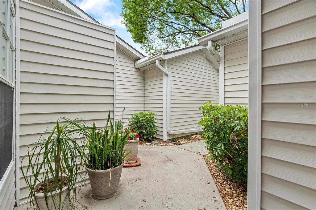 A concrete patio area is nestled between the beige vinyl-sided walls of a house — 21506 GRAY TERN COURT, LUTZ, FL