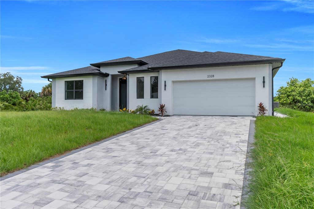 A modern, single-story house with a white exterior, dark roof, and a paved driveway — 2328 IRONDALE RD, NORTH PORT, FL