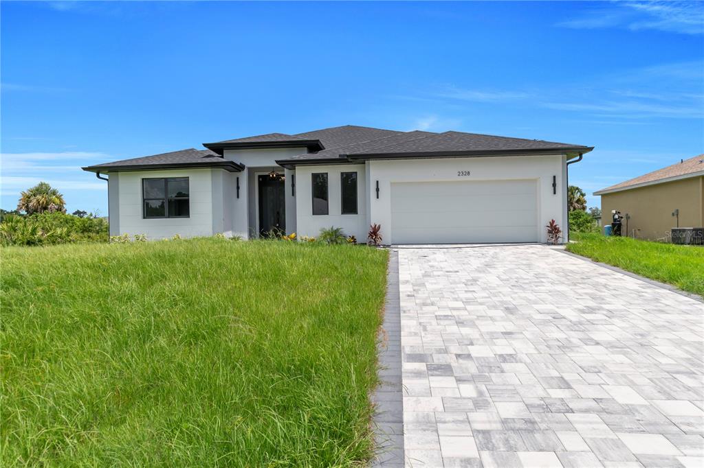 A modern, single-story house with a white exterior, dark roof, and a paved driveway — 2328 IRONDALE RD, NORTH PORT, FL