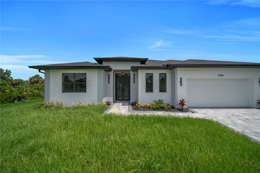 A modern single-story house with a white exterior, a two-car garage, and a paved walkway — 2328 IRONDALE RD, NORTH PORT, FL