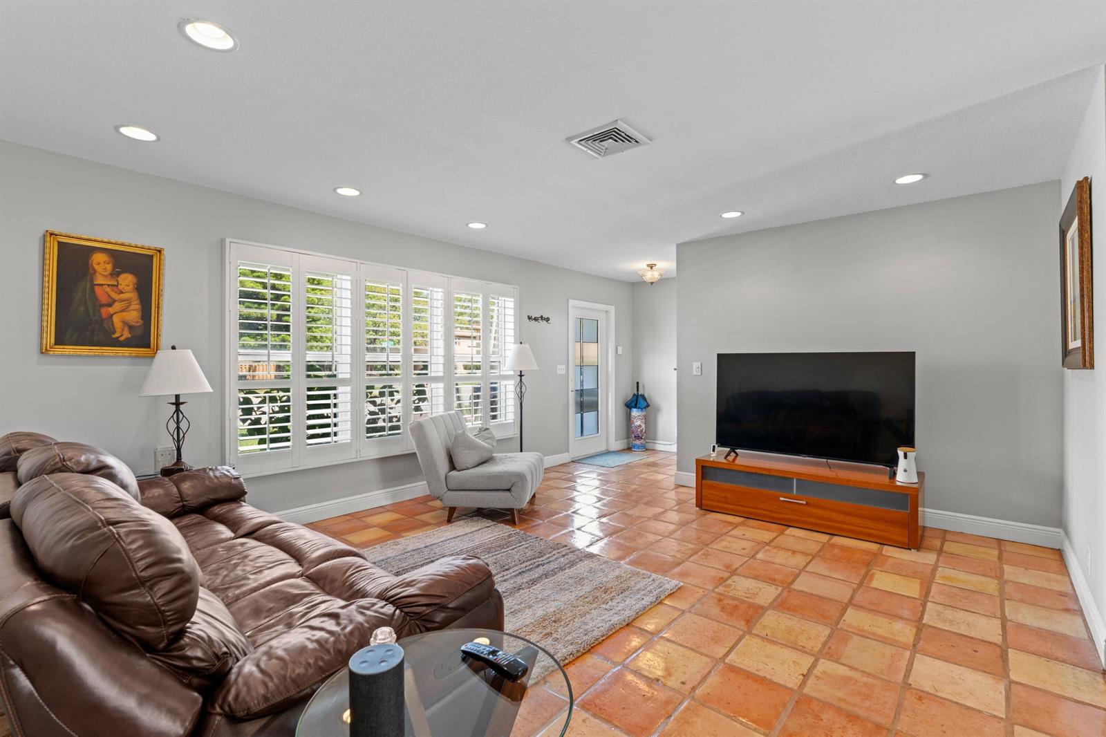 A living room features a brown leather sofa, a television on a stand, and tile flooring — 200 SW 5th Street, Boca Raton FL 33432, BOCA RATON, FL