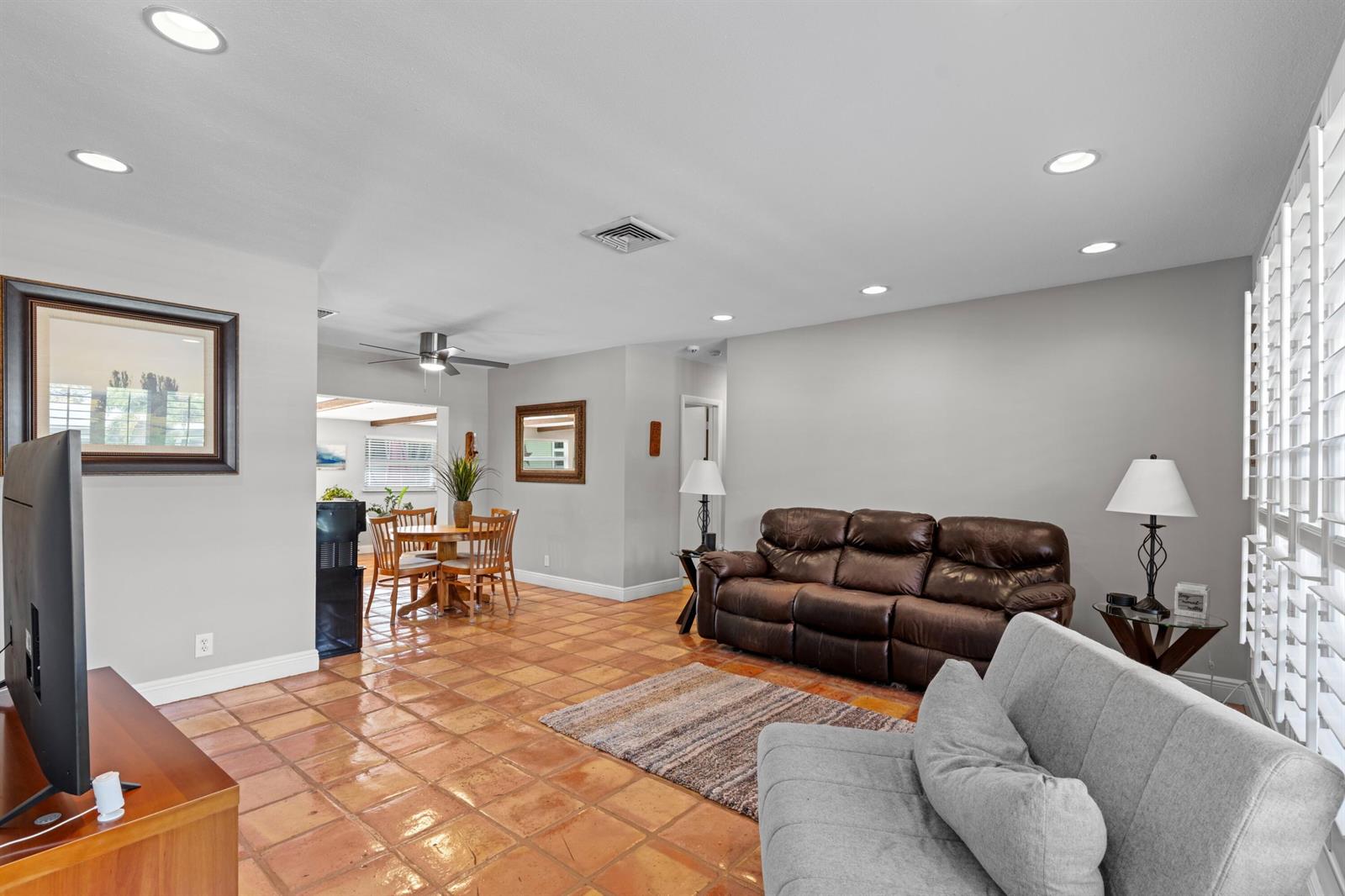 A living room with terracotta tile floors, a brown leather sofa, and a dining area — 200 SW 5th Street, Boca Raton FL 33432, BOCA RATON, FL