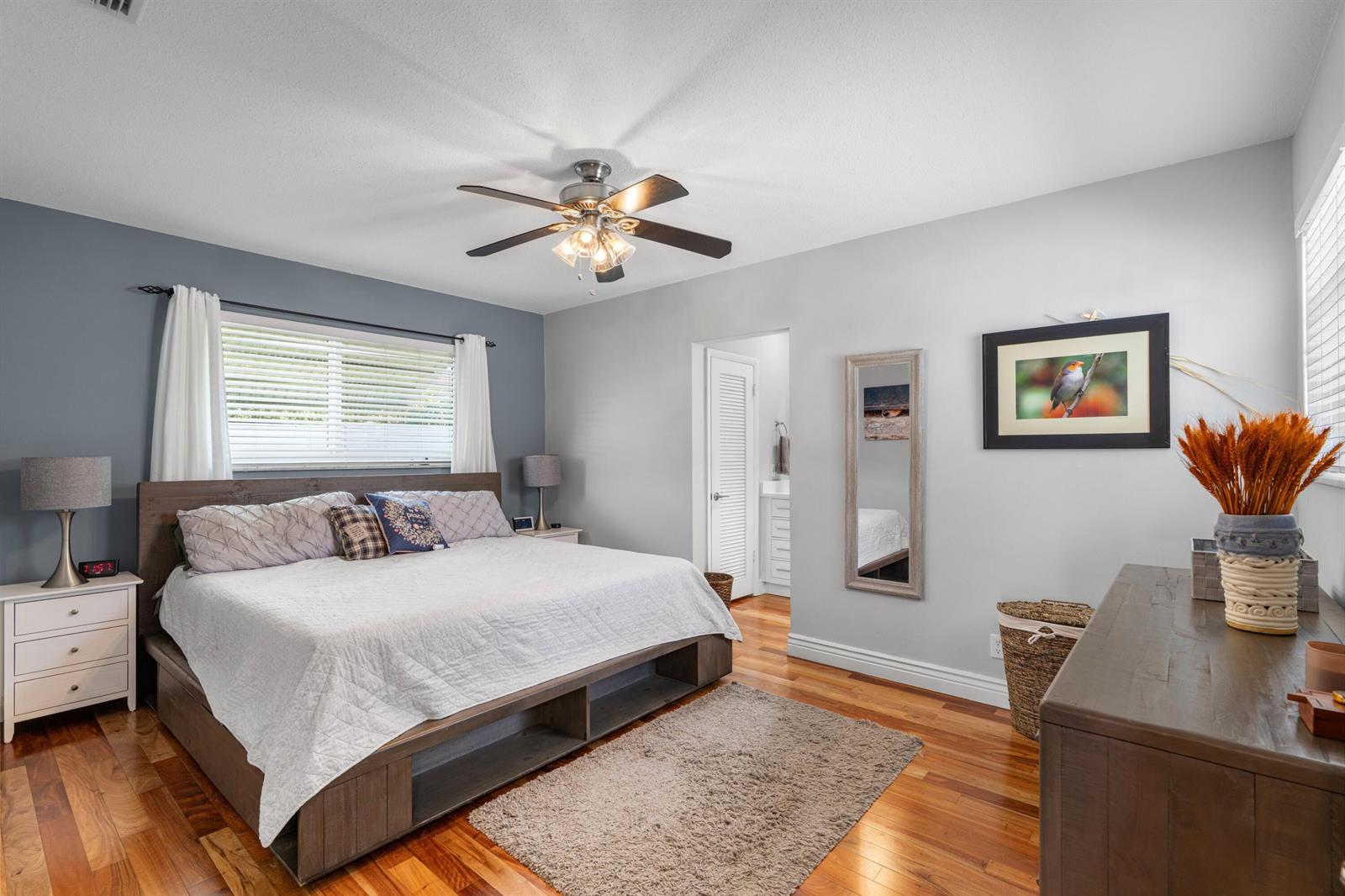 A bedroom features a wooden platform bed, hardwood floors, a ceiling fan, and gray walls — 200 SW 5th Street, Boca Raton FL 33432, BOCA RATON, FL