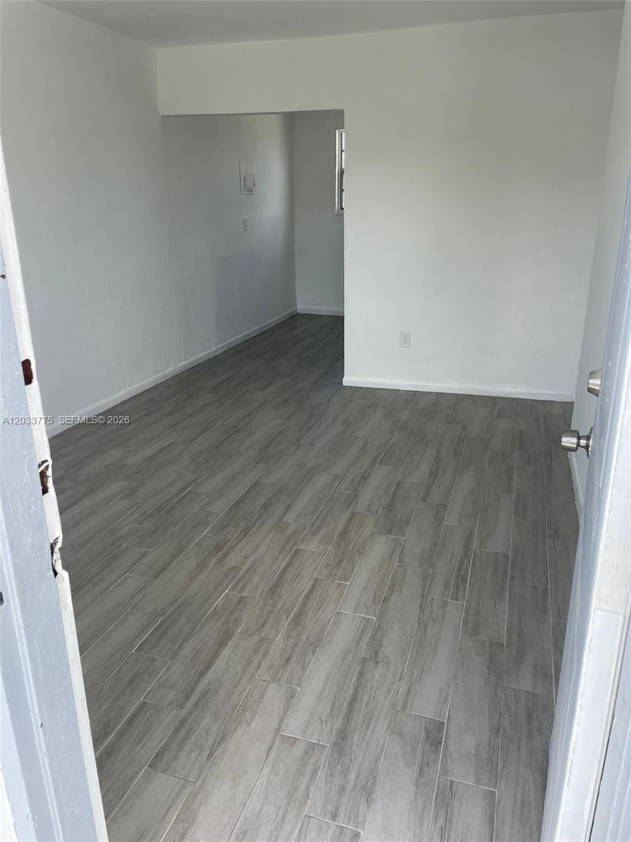 An empty room features light gray wood-look tile flooring and plain white walls — 1261 NW 59th St # 14, Miami FL 33142, MIAMI, FL