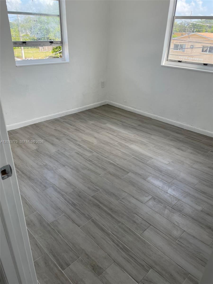 An empty room features white walls, two windows, and light gray wood-look tile flooring — 1261 NW 59th St # 14, Miami FL 33142, MIAMI, FL