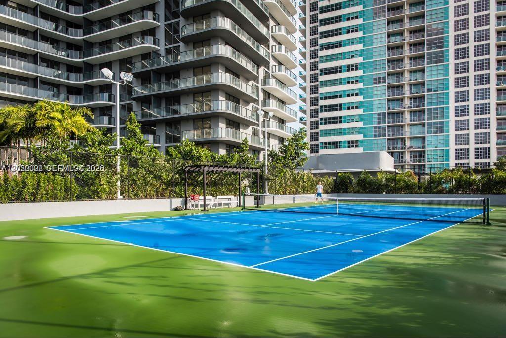 A blue tennis court sits in front of a modern high-rise apartment building — 121 NE 34th St # 2203, Miami FL 33137, MIAMI, FL