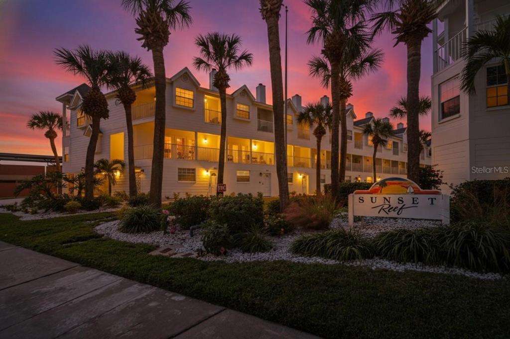 A multi-story white apartment building with palm trees at sunset — 17960 GULF BOULEVARD UNIT 104, REDINGTON SHORES, FL
