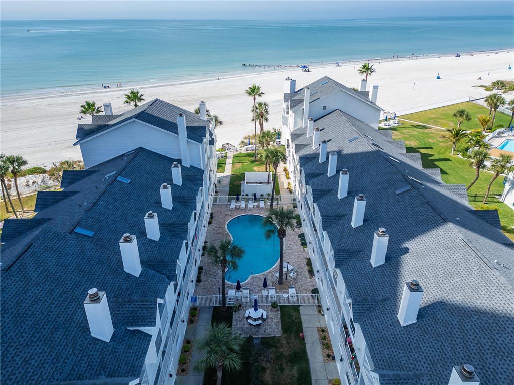 An aerial view shows two white buildings flanking a swimming pool near a sandy beach — 17960 GULF BOULEVARD UNIT 104, REDINGTON SHORES, FL