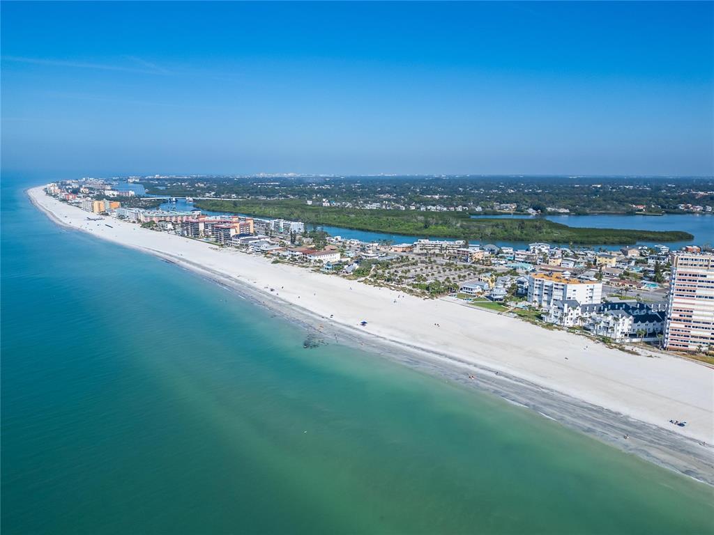 An aerial view shows a sandy beach along the ocean with coastal buildings and vegetation — 17960 GULF BOULEVARD UNIT 104, REDINGTON SHORES, FL