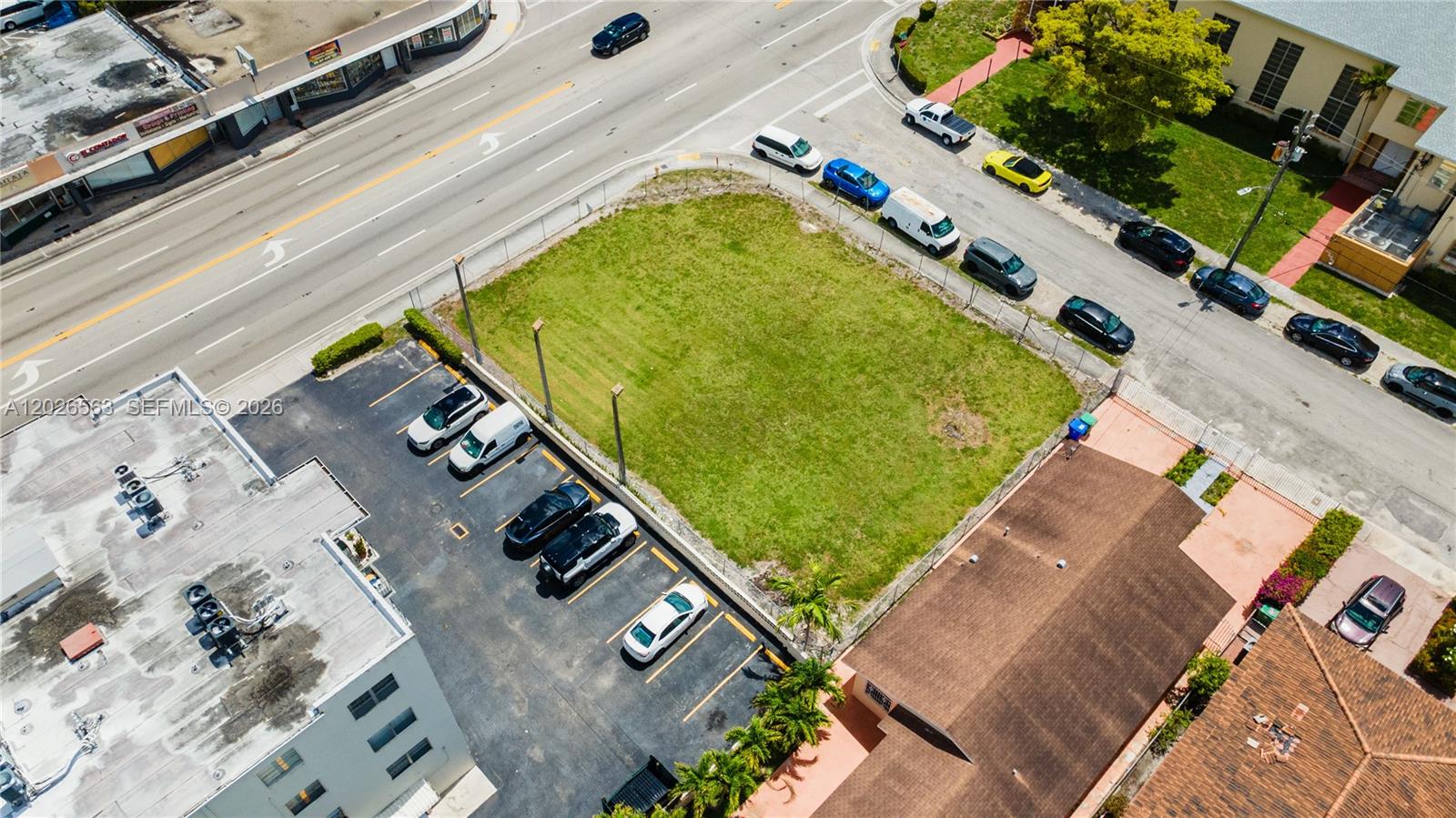An aerial view shows a vacant grassy lot bordered by a parking lot and streets — 5895 W Flagler St, Miami FL 33144, MIAMI, FL
