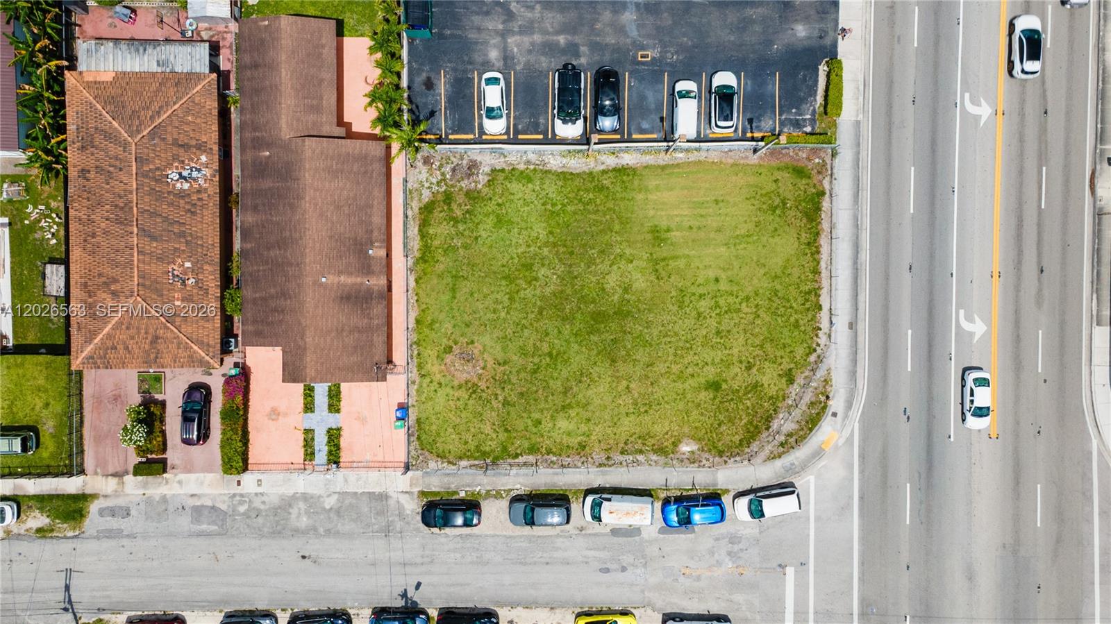 An aerial view shows a vacant grassy lot situated between a building and a road — 5895 W Flagler St, Miami FL 33144, MIAMI, FL
