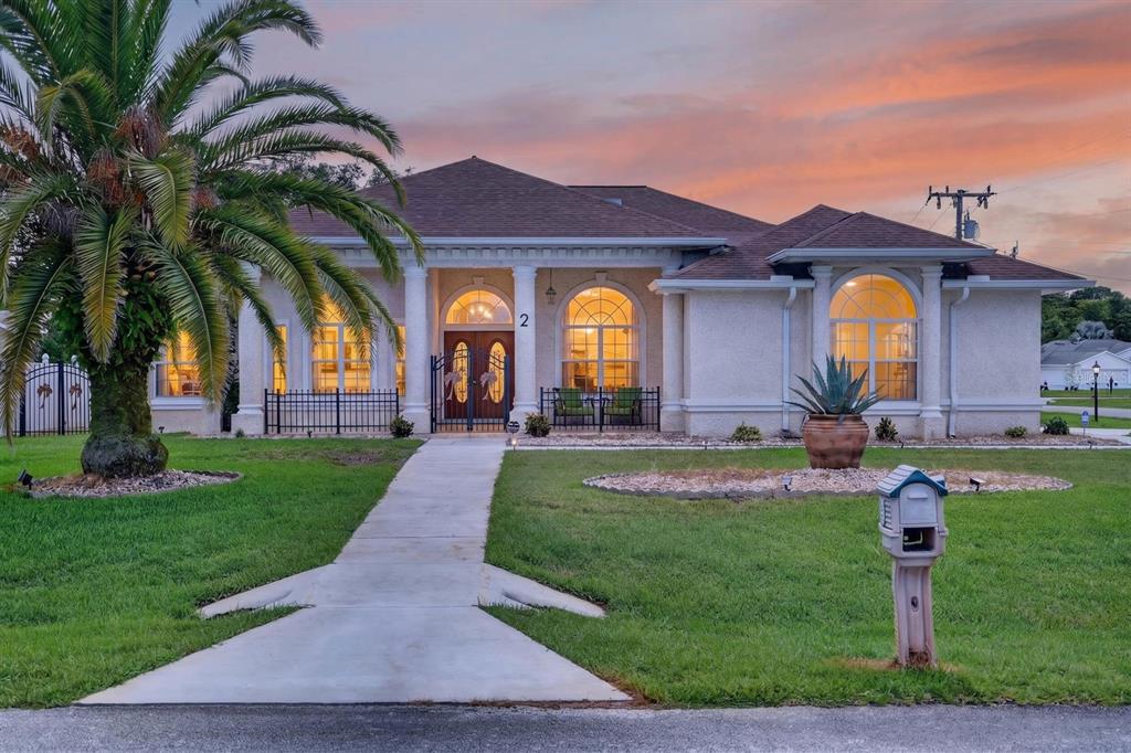 A single-story house with a palm tree, arched windows, and a concrete walkway at sunset — 2 FORGE LANE, PALM COAST, FL