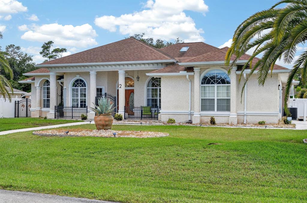 A single-story house with a stucco exterior, arched windows, and a front porch with columns — 2 FORGE LANE, PALM COAST, FL