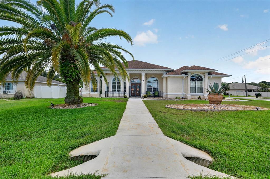 A single-story house with a palm tree in the front yard and a concrete walkway — 2 FORGE LANE, PALM COAST, FL