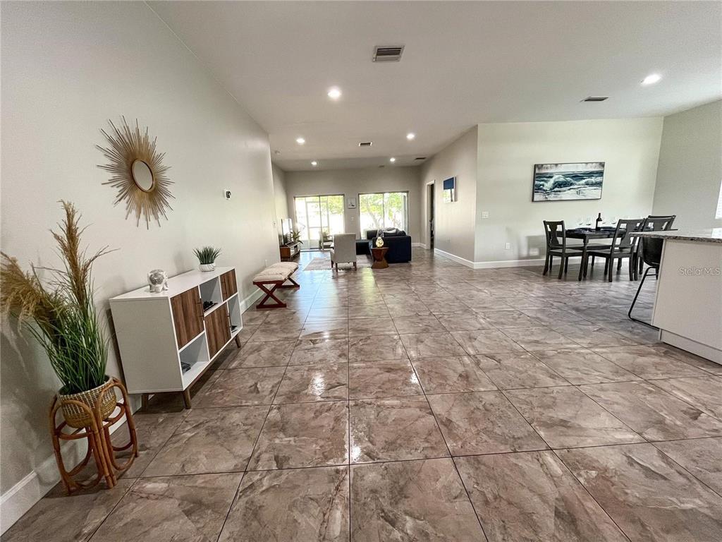An open-concept living and dining area features large neutral floor tiles and recessed lighting — 5119 RILMA AVENUE, SARASOTA, FL