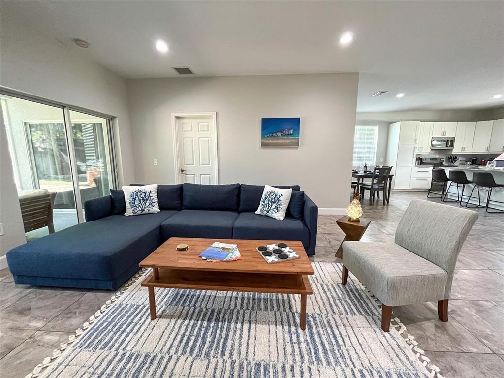 A living room features a blue sectional sofa, a wooden coffee table, and an accent chair — 5119 RILMA AVENUE, SARASOTA, FL