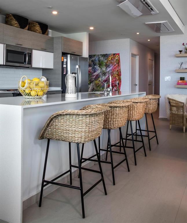 A modern kitchen features a white island with woven bar stools and gray cabinetry — 1511 22 PONCE DE LEON AVE. UNIT 9151, SAN JUAN, PR
