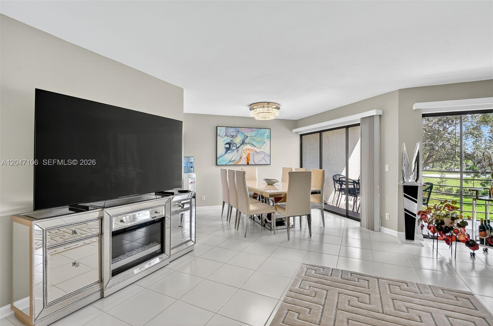 A screened-in balcony features a dining table, blue chairs, and views of palm trees — 5901 Camino Del Sol # 207, Boca Raton FL 33433, BOCA RATON, FL