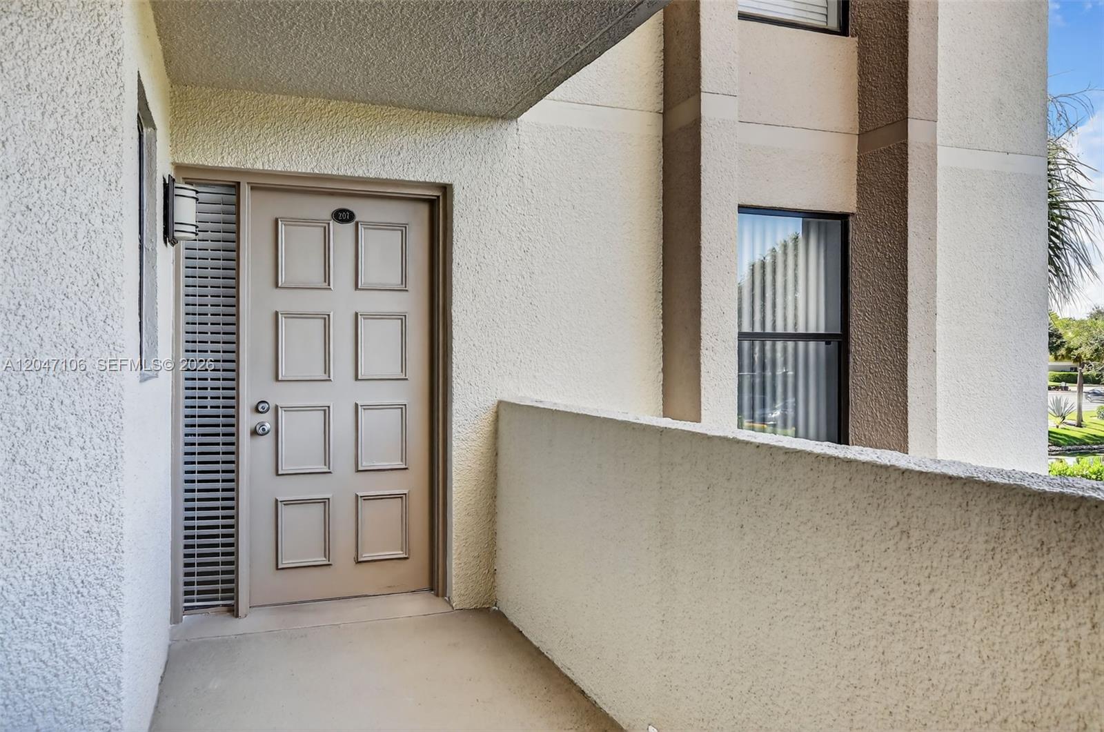 A kitchen features medium-toned wood cabinets, stainless steel appliances, and speckled granite countertops — 5901 Camino Del Sol # 207, Boca Raton FL 33433, BOCA RATON, FL