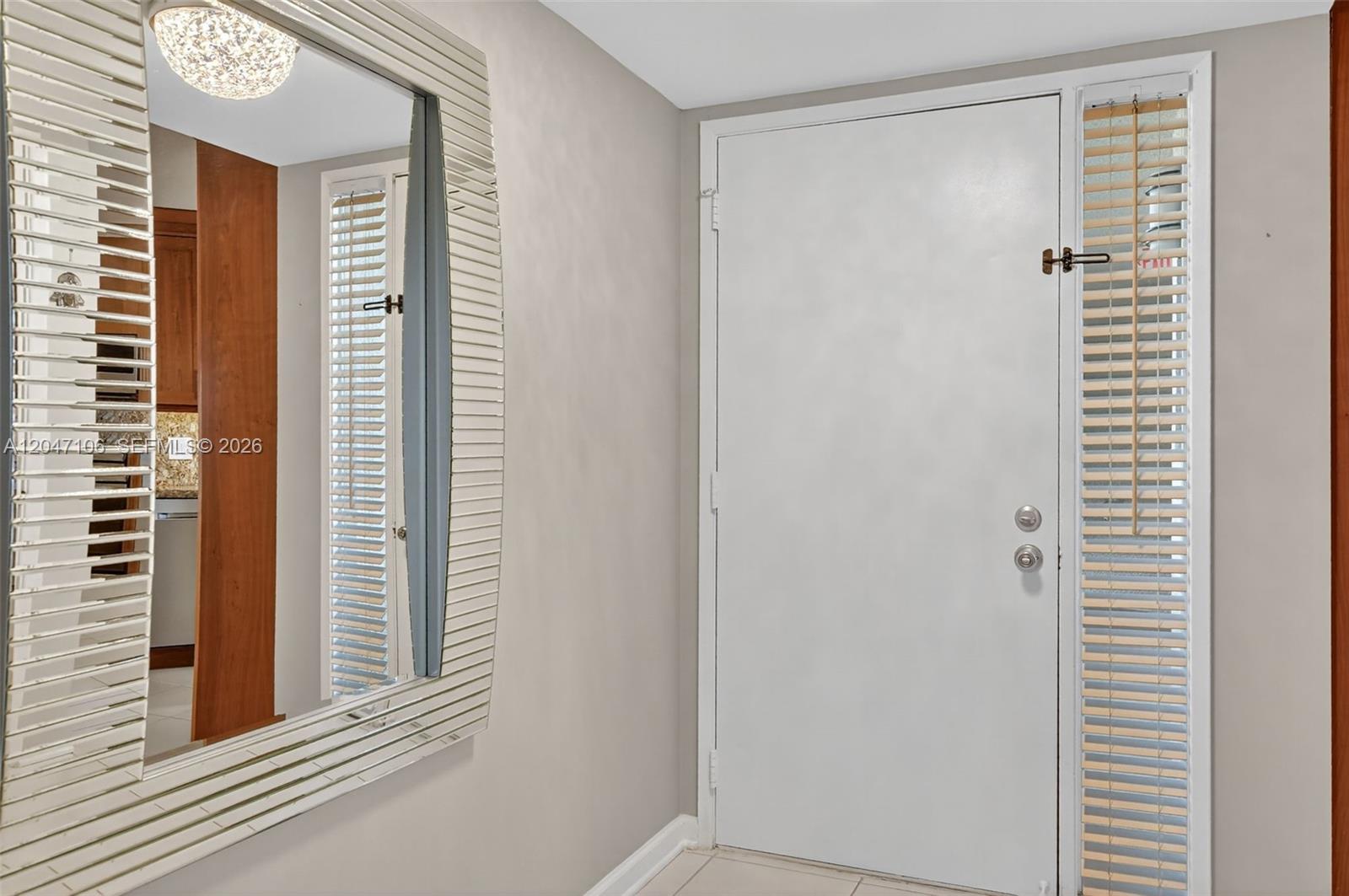A bedroom features white furniture, a gray quilted bedspread, and a sliding glass door balcony — 5901 Camino Del Sol # 207, Boca Raton FL 33433, BOCA RATON, FL