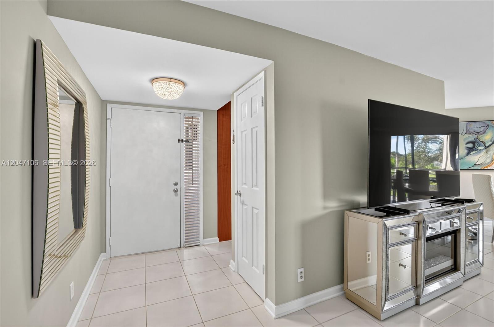 A living and dining area features light tile floors, a beige sectional, and sliding glass doors — 5901 Camino Del Sol # 207, Boca Raton FL 33433, BOCA RATON, FL