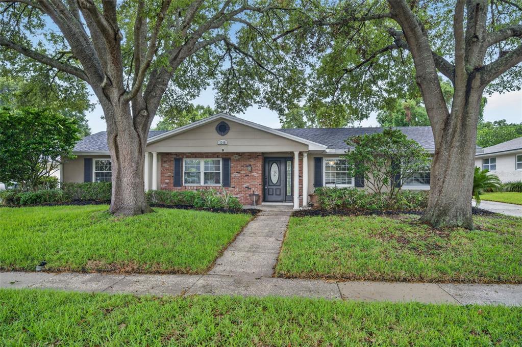 A single-story brick and siding house with a front walkway framed by two large trees — 3240 TOURAINE AVENUE, ORLANDO, FL