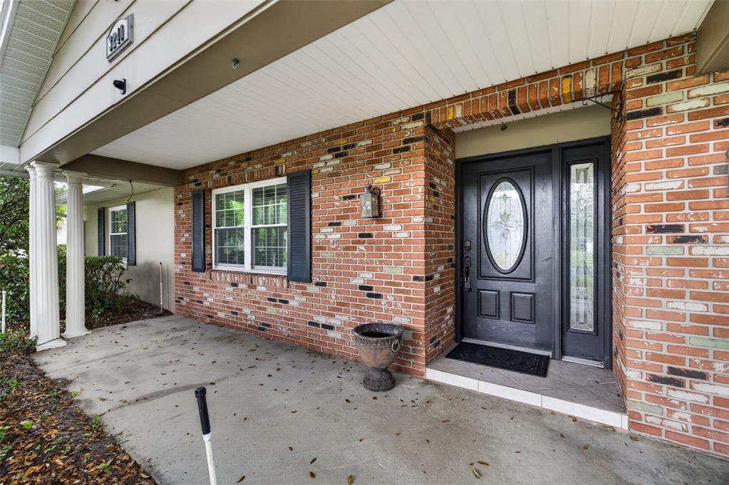 A brick house exterior features a covered porch, a black front door, and white columns — 3240 TOURAINE AVENUE, ORLANDO, FL