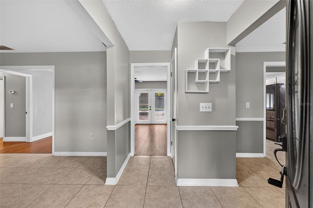 An interior view of a tiled entryway featuring gray walls, white trim, and a wall shelf — 3240 TOURAINE AVENUE, ORLANDO, FL