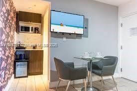 A small kitchenette with a microwave and mini-fridge sits beside a dining table and chairs — 7310 Harding Ave # 1, Miami Beach FL 33141, MIAMI BEACH, FL