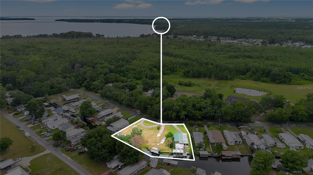 An aerial view shows a waterfront property with a small house and boat dock — 13450 PALM DRIVE, ASTATULA, FL