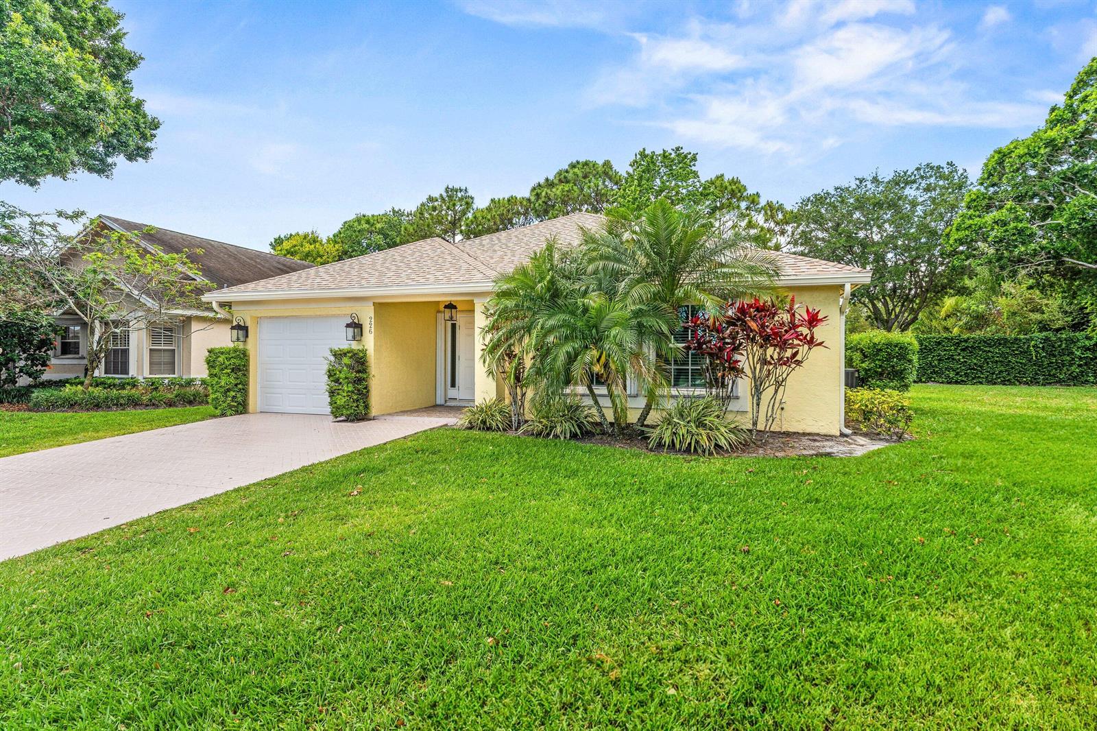 A yellow single-story house with a white garage door and a palm tree-filled front yard — 226 Moccasin Trail W, Jupiter FL 33458, JUPITER, FL
