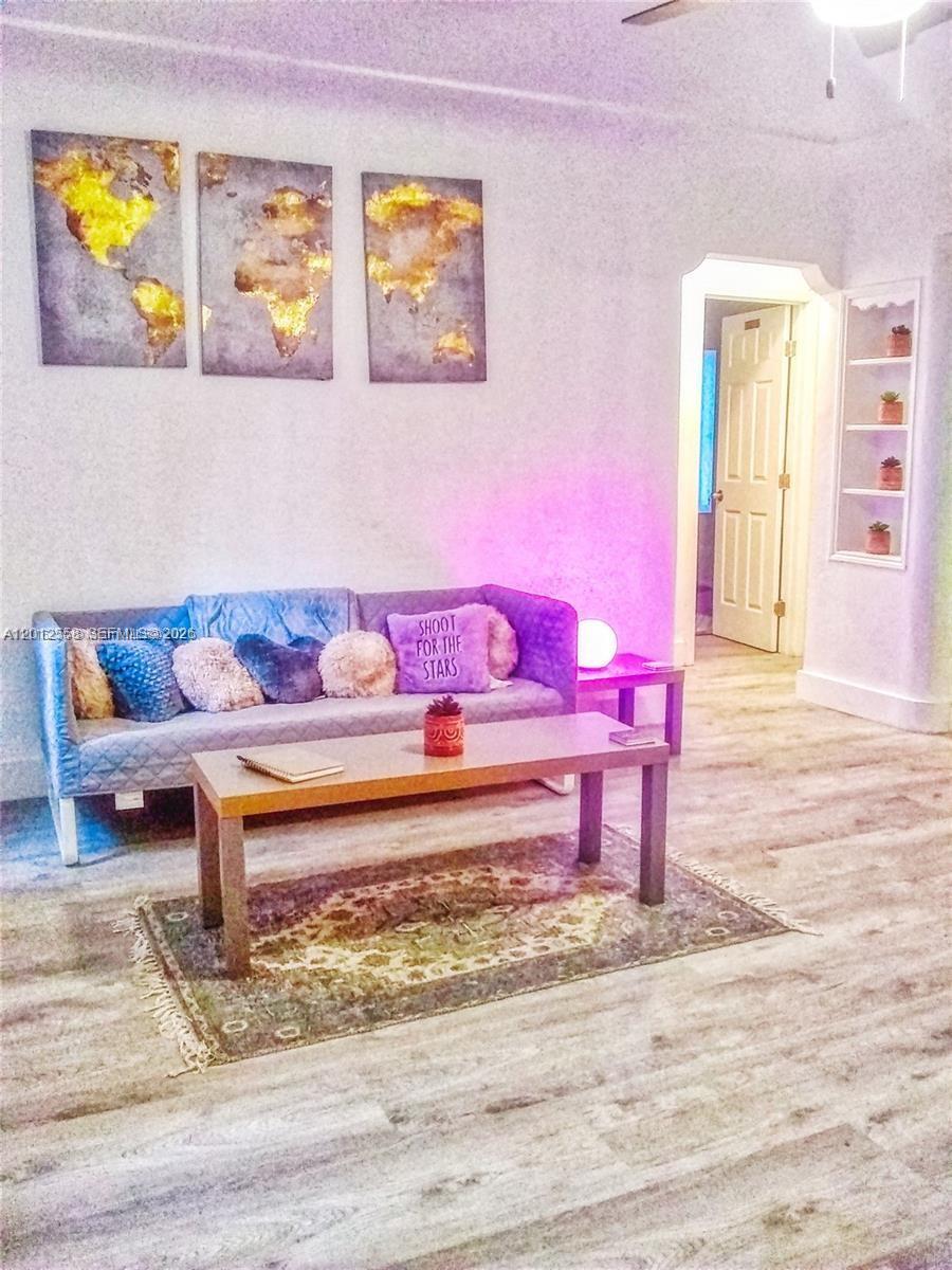 A living room features a gray sofa, a coffee table, and wall art — 142 NE 56th St # A, Miami FL 33137, MIAMI, FL
