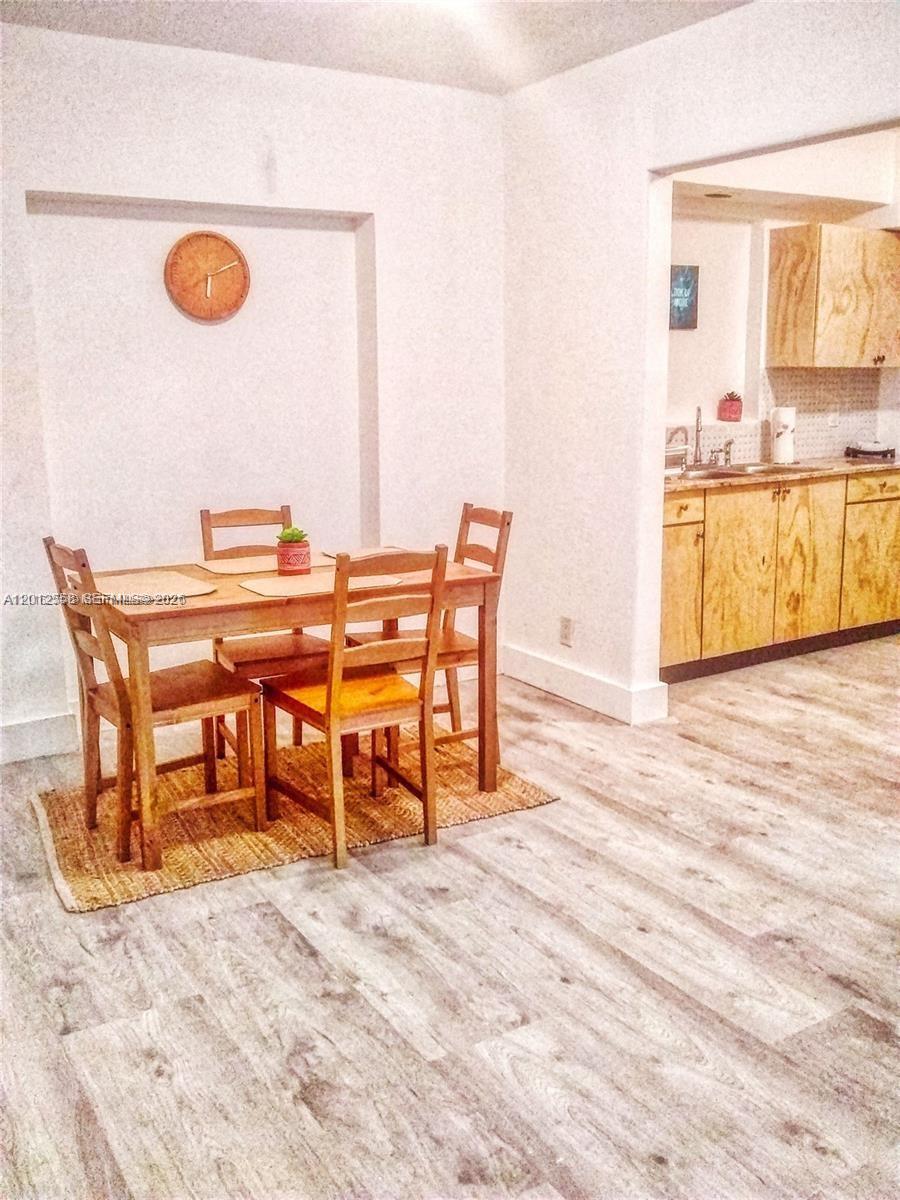 A dining area with a wooden table and chairs sits adjacent to a kitchen — 142 NE 56th St # A, Miami FL 33137, MIAMI, FL