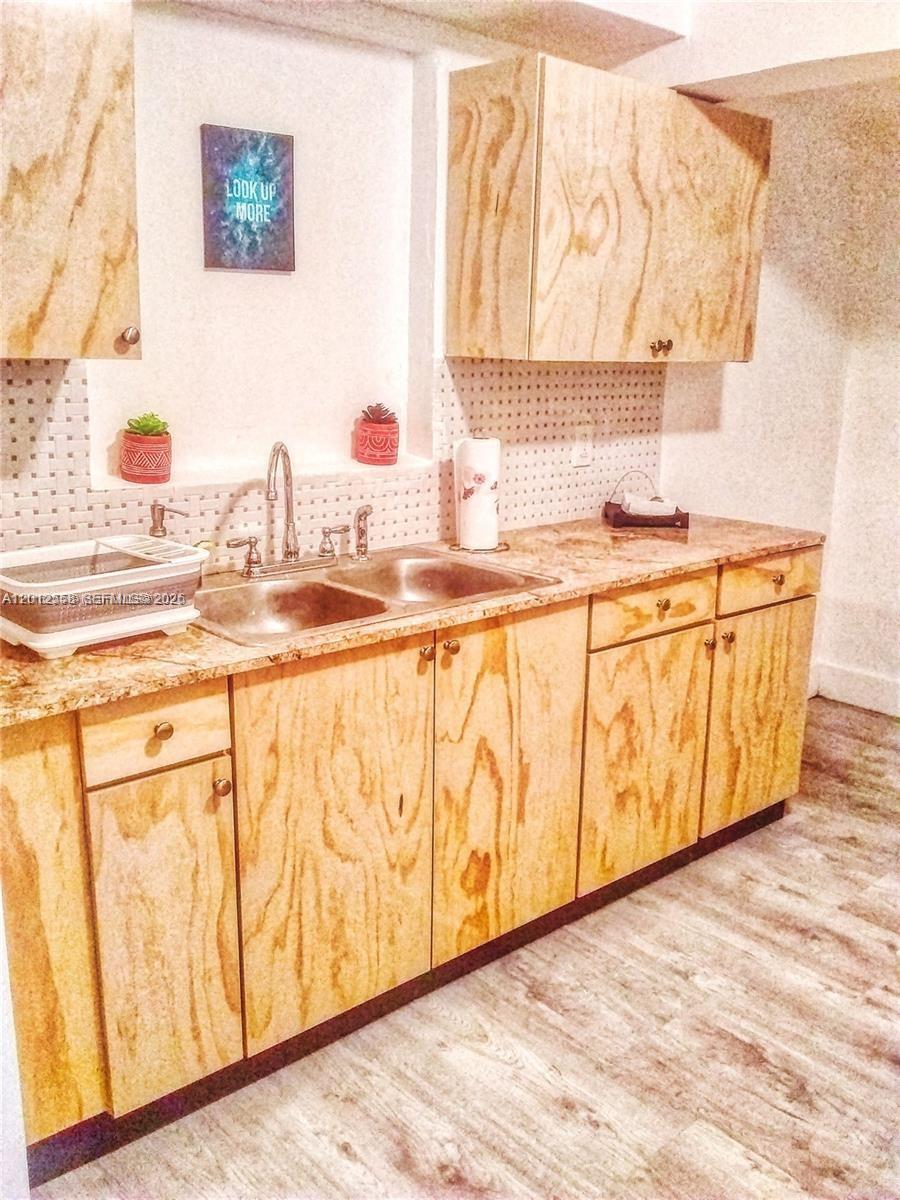 A kitchen features plywood cabinets, a granite countertop, a double sink, and a pegboard backsplash — 142 NE 56th St # A, Miami FL 33137, MIAMI, FL