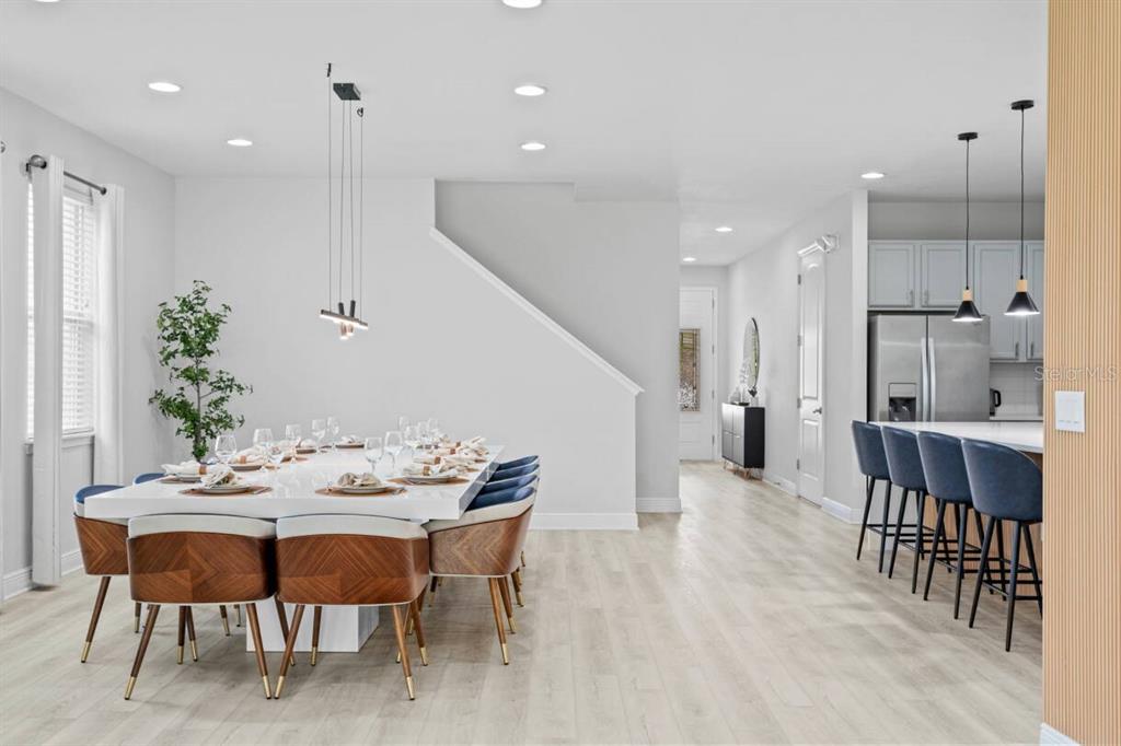 A dining area with a large table and blue chairs sits adjacent to a kitchen island — 451 BURMA STREET, KISSIMMEE, FL