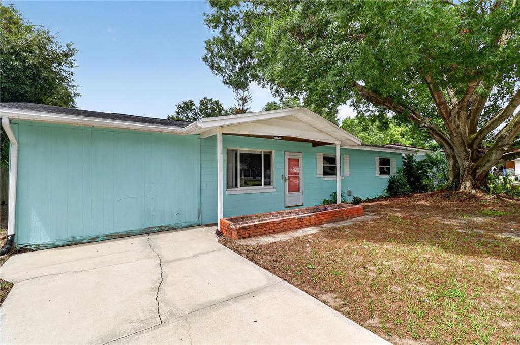 A light blue, single-story house with a concrete driveway and a brick planter box — 120 E HOFFMAN ST, LAKE ALFRED, FL