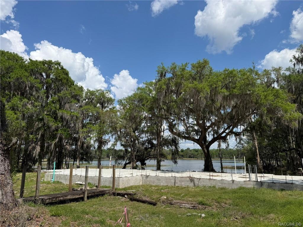 A concrete foundation sits on a grassy lot overlooking a lake with large trees — 5765 N CARL G ROSE HIGHWAY, HERNANDO, FL