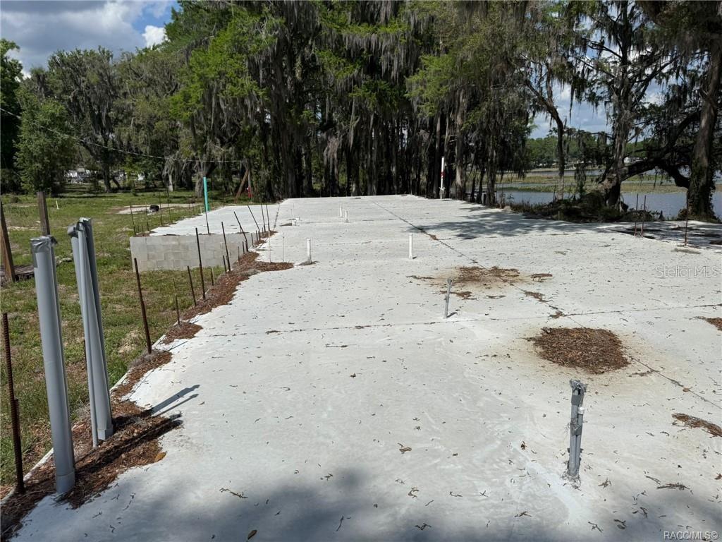 A concrete foundation slab with plumbing pipes sits on a waterfront lot with trees — 5765 N CARL G ROSE HIGHWAY, HERNANDO, FL